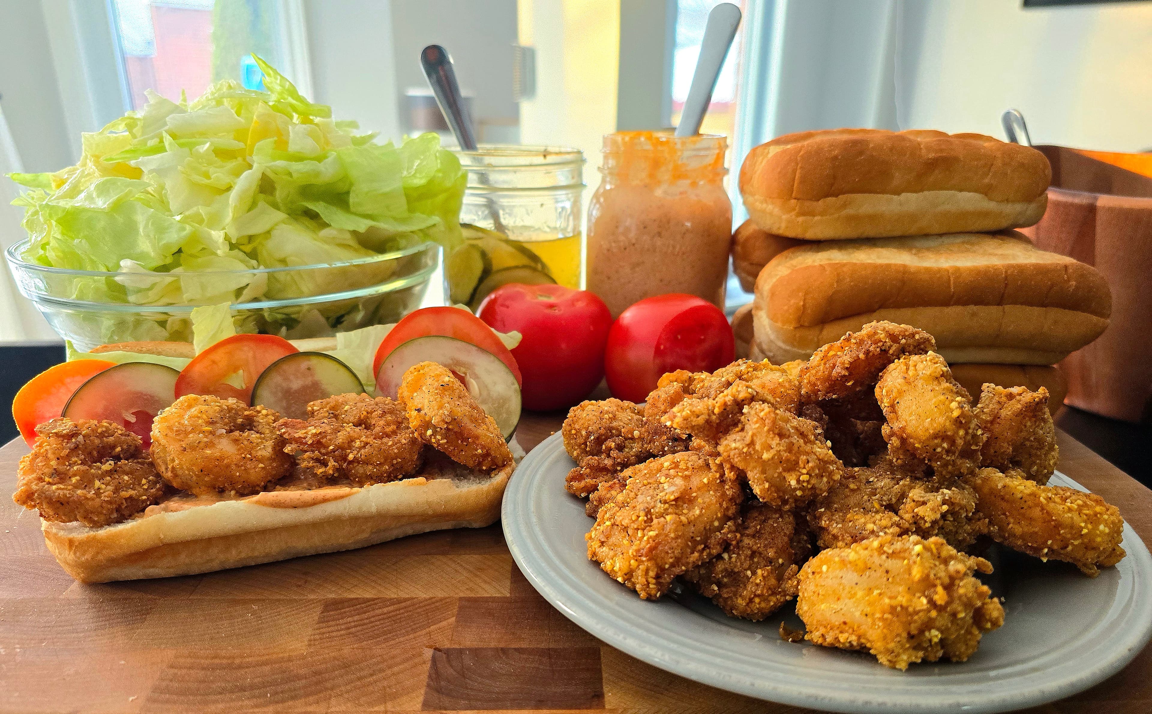 Homemade shrimp po'boys with fixings laid out on the counter